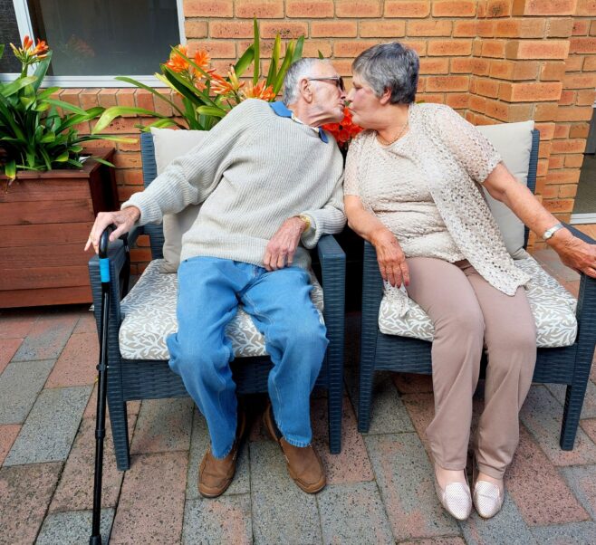 Elderly couple share a kiss on an outdoor bench