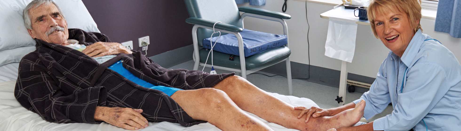 Patient receiving foot massage in hospital bed