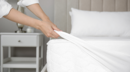 Housekeeper folds corner of white bedsheets