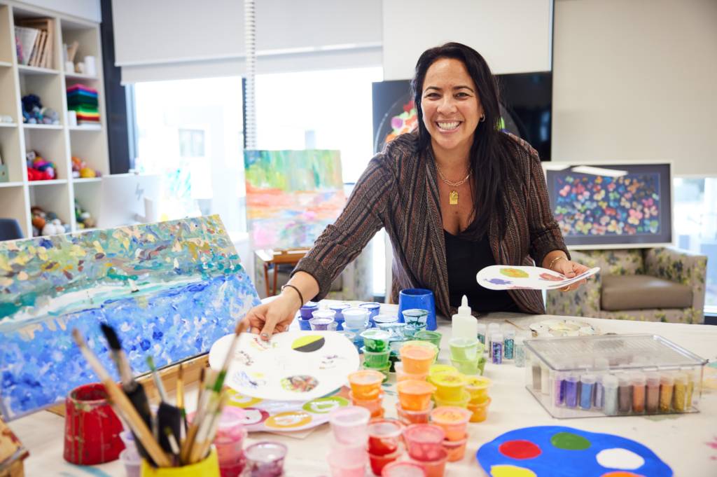 female art therapist sets up paints and brush sets for patients attending therapy class