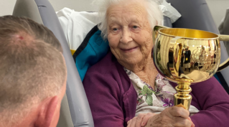 Elderly female resident at Calvary St Joseph's aged care home holding the melbourne cup