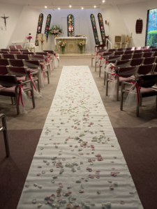 an aisle in a chapel covered in flowers