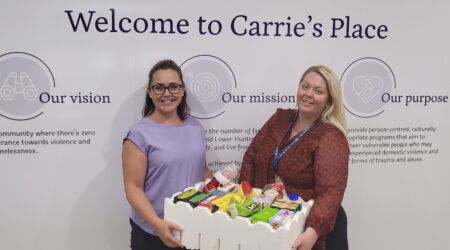 two ladies posing with a box of donations
